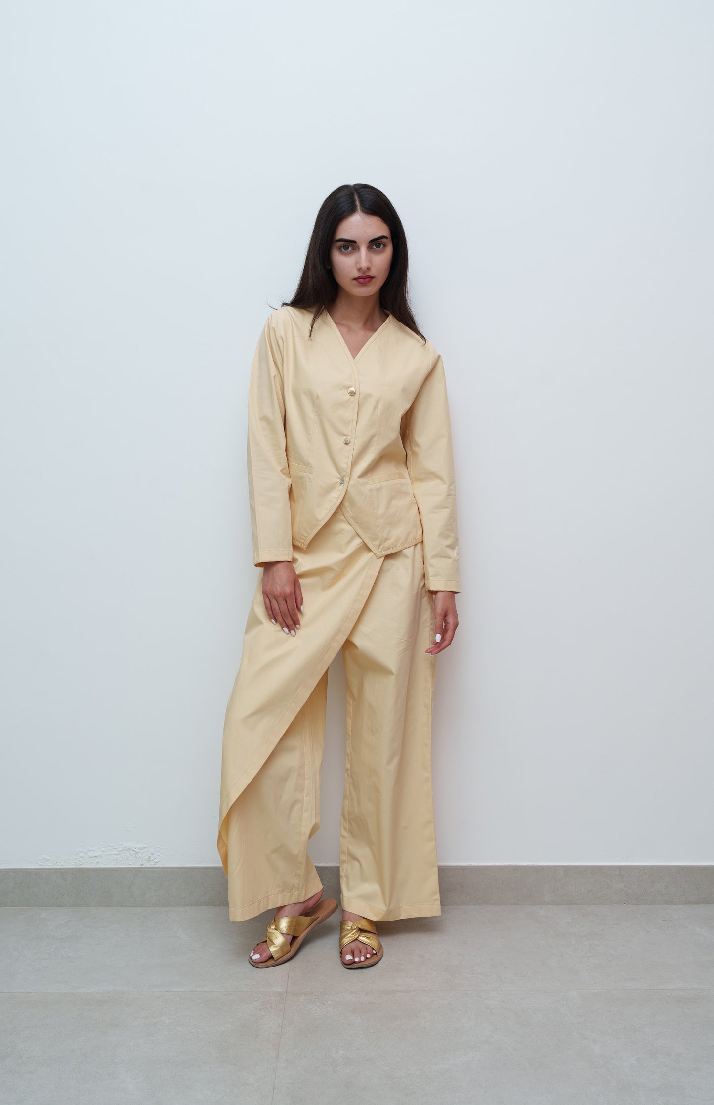 Woman wearing a beige outfit against a plain background