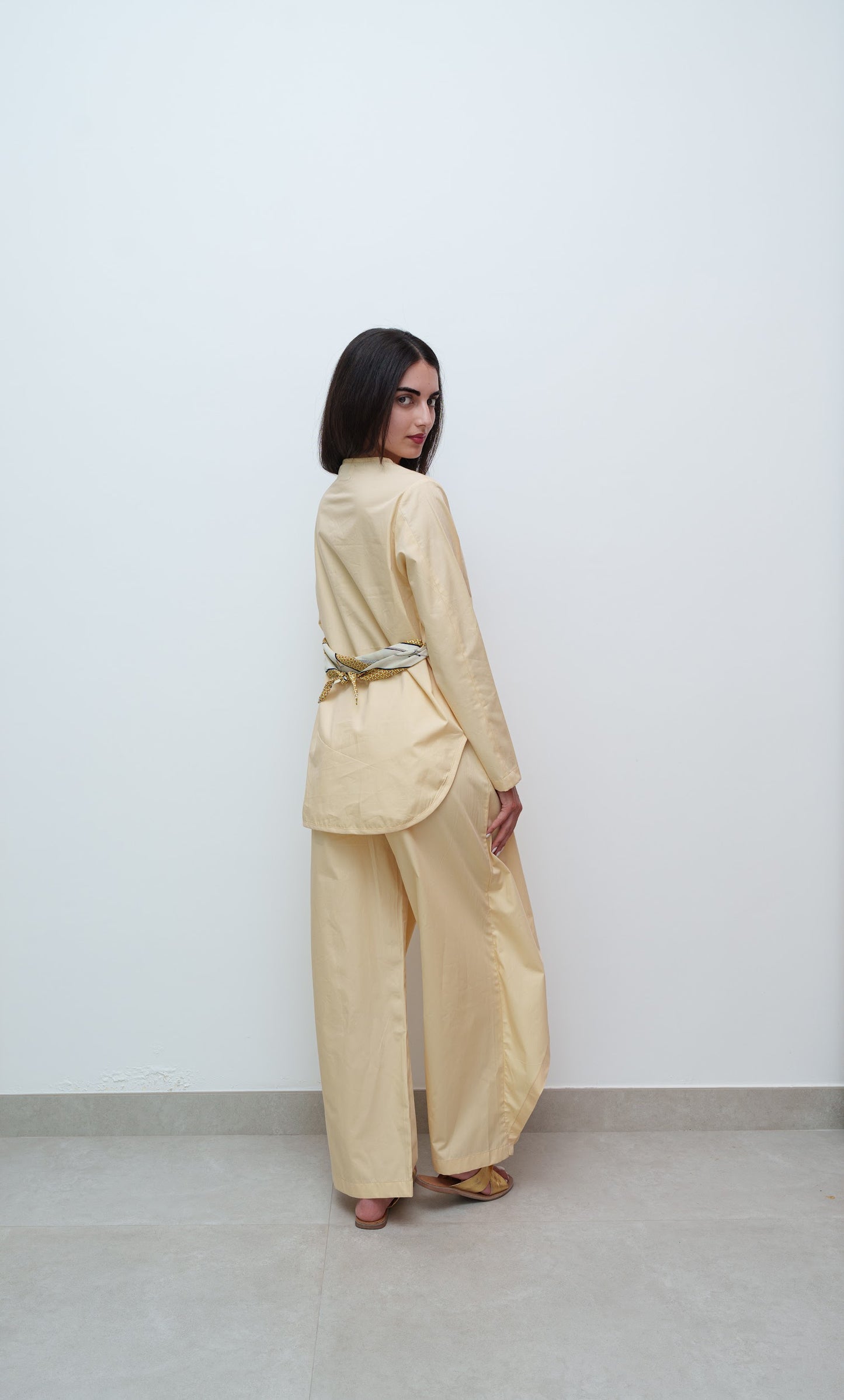 Woman wearing a beige outfit with a belt against a white background