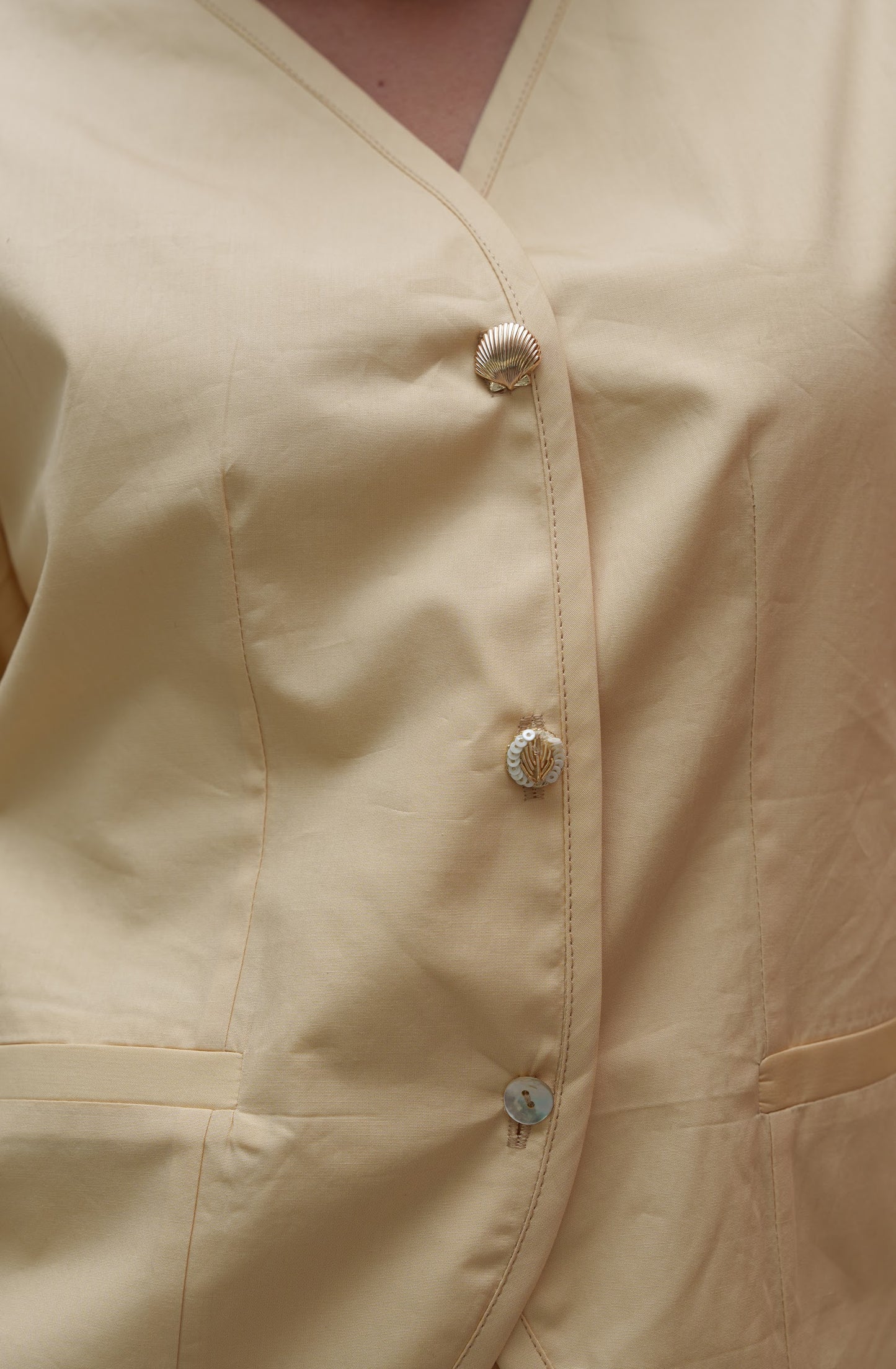Close-up of a beige shirt with buttons on a plain background