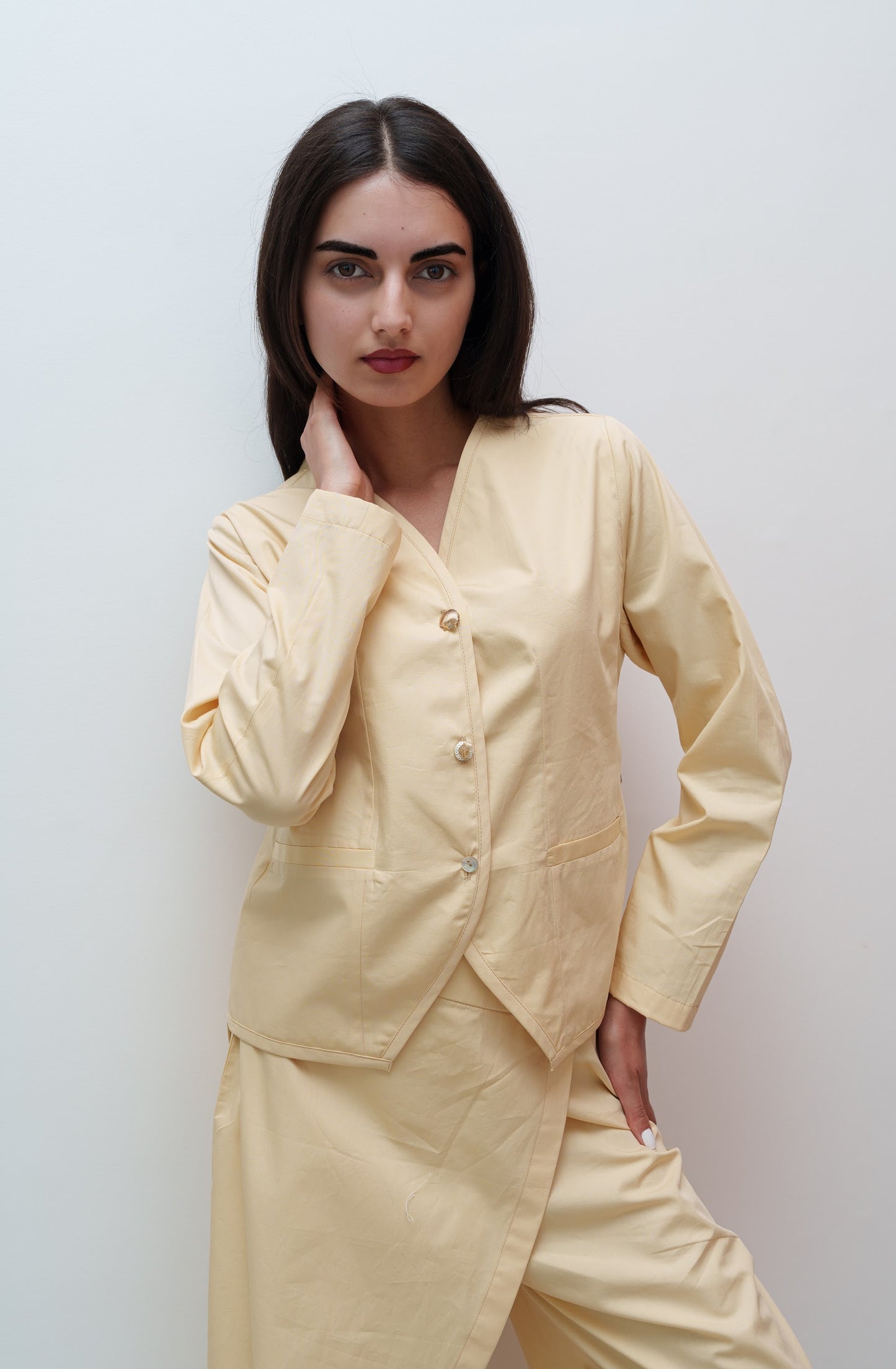 Woman wearing a beige outfit against a plain background