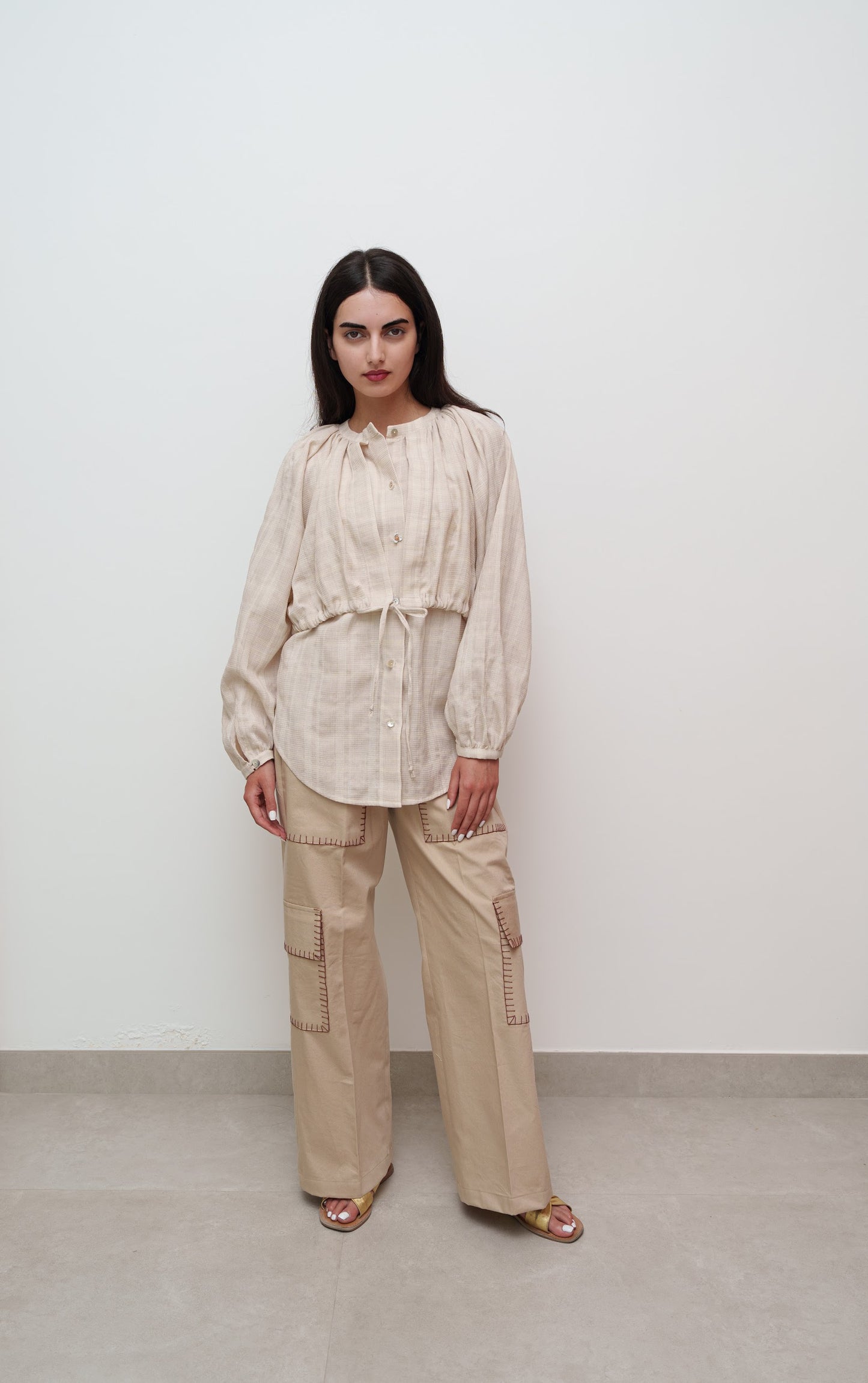 Woman wearing a beige outfit against a white background