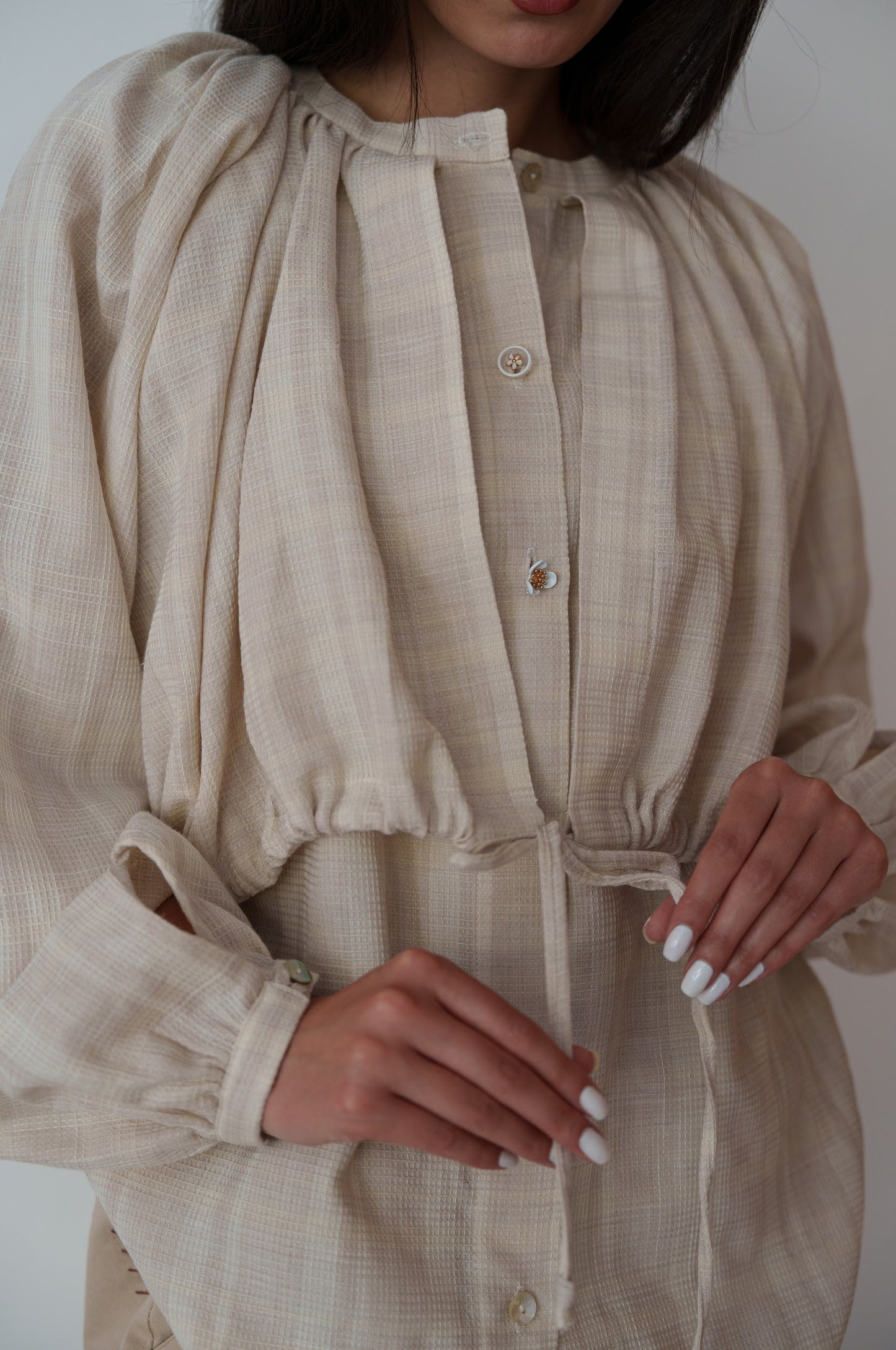 Beige dress with long sleeves and a tie waist, worn by a person.