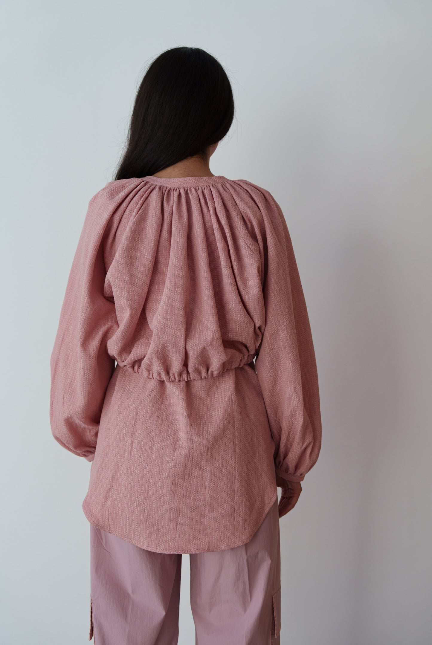 Person wearing a pink outfit against a plain background