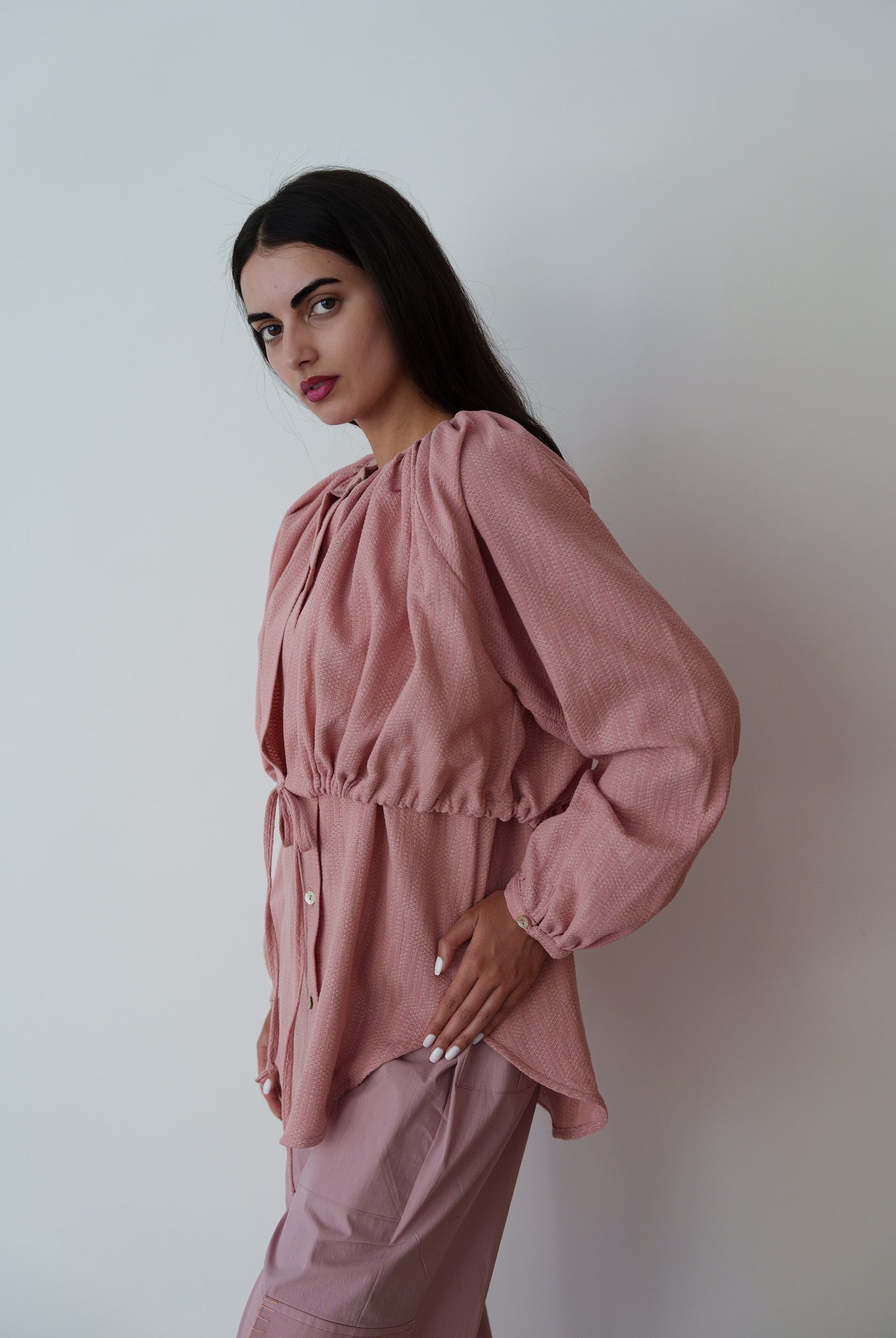Woman wearing a pink outfit against a plain background