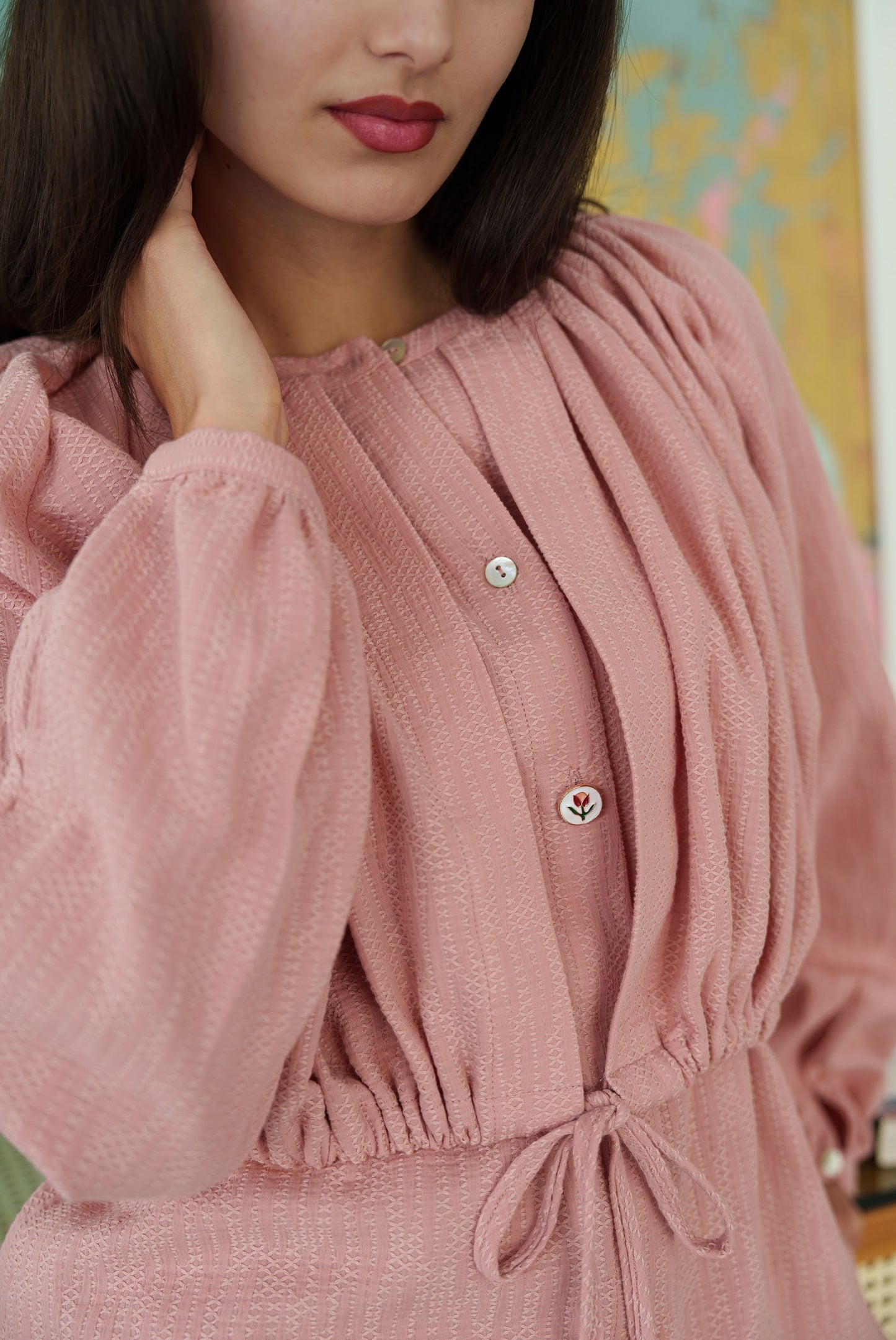 Close-up of a person wearing a pink textured dress with a blurred background