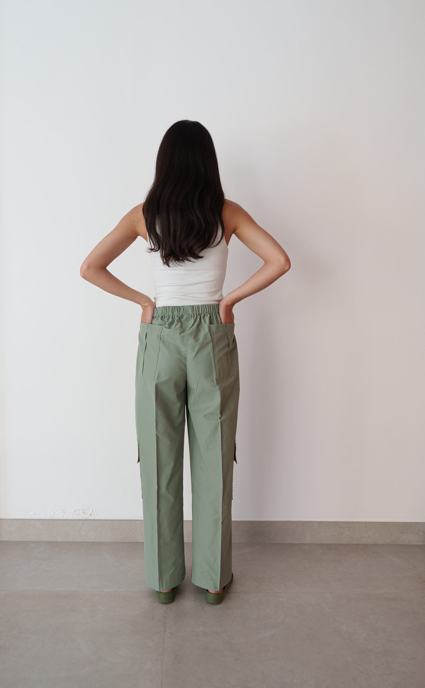 Person wearing a white top and green pants against a plain background
