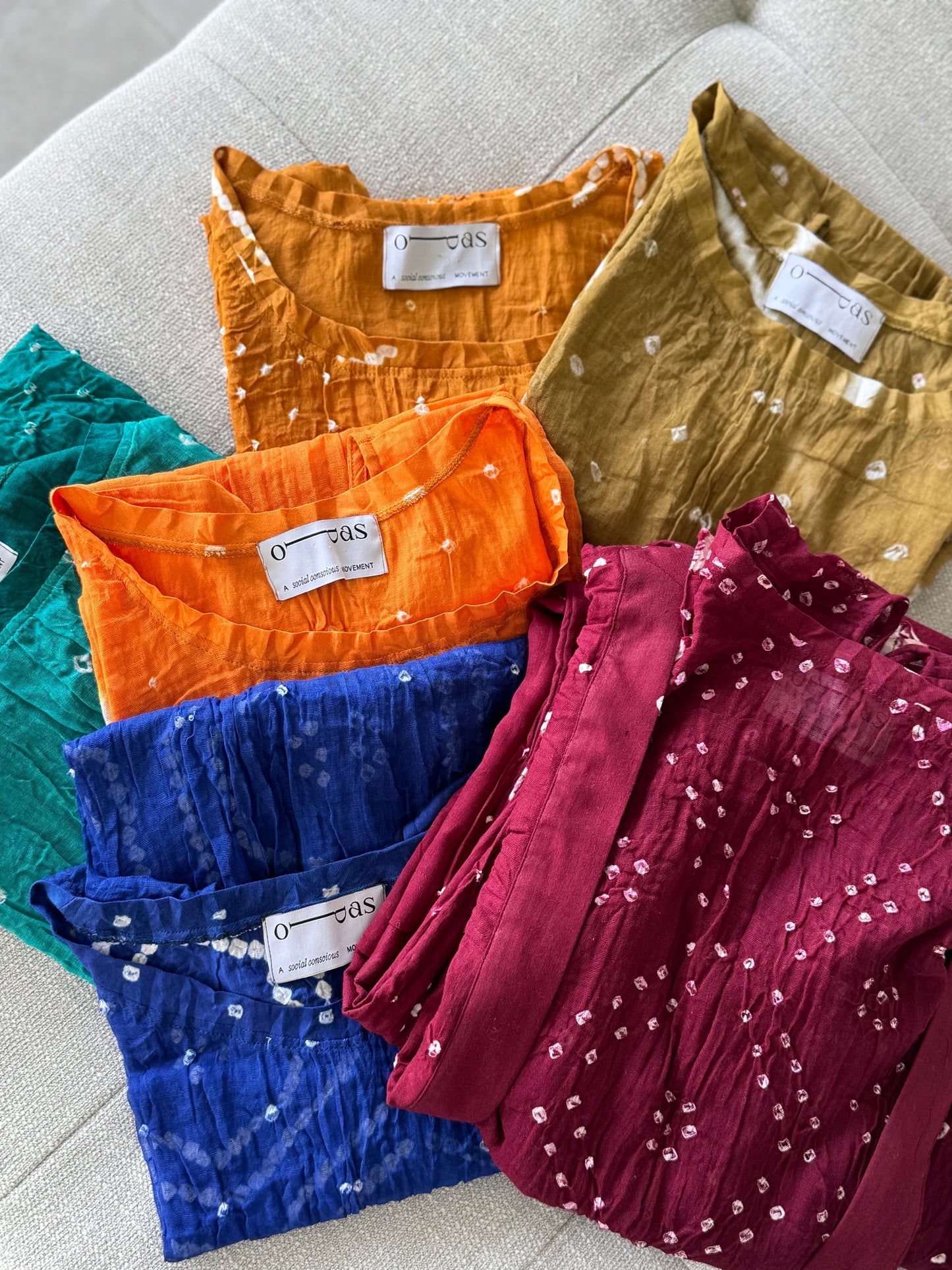 Five colorful tops with labels on a light gray surface