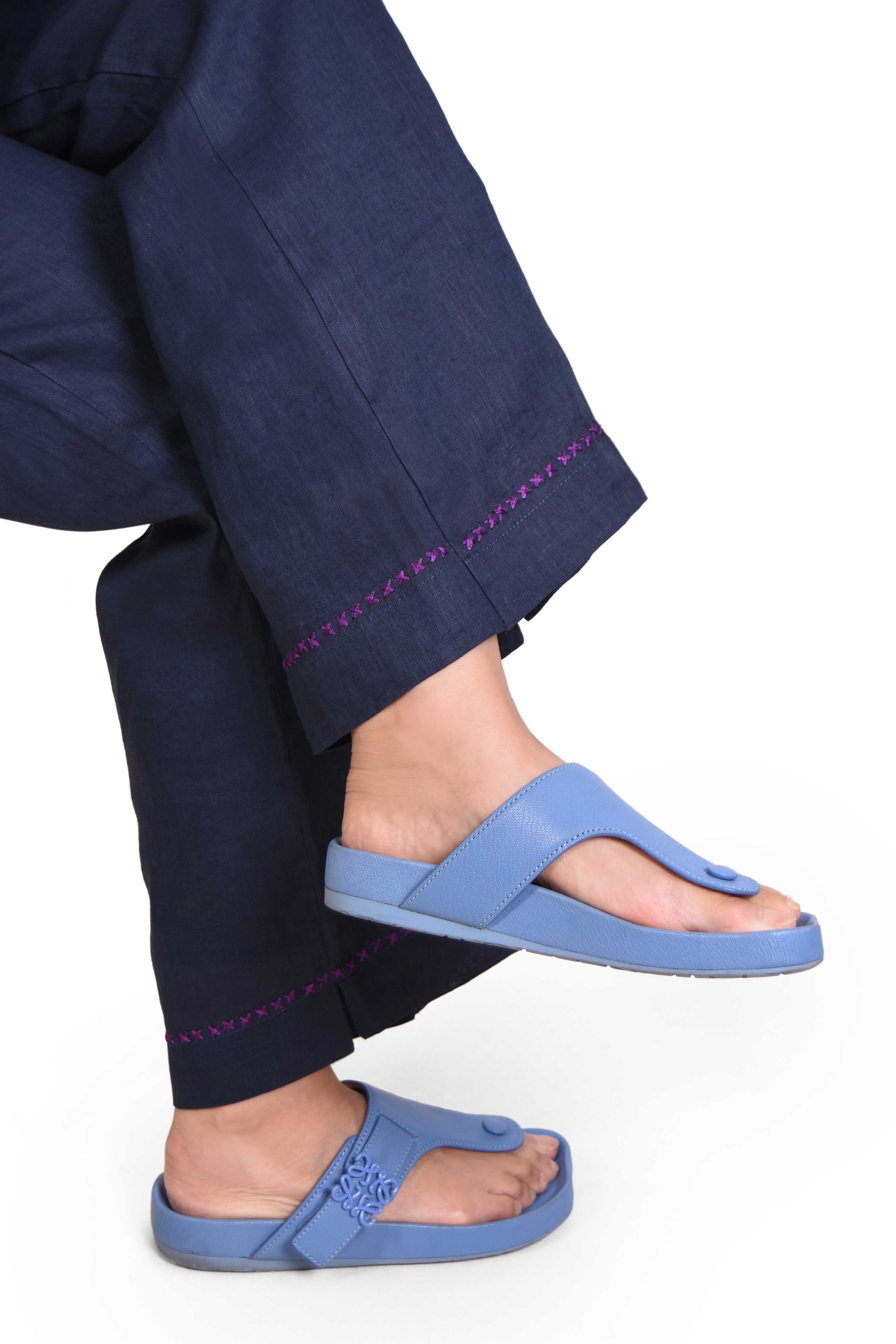 Person wearing blue sandals with navy pants, Indian Linen,  on a white background