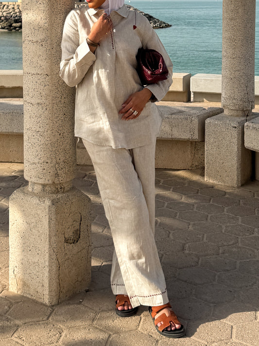 Women wearing a light-toned outfit by stone pillars overlooking a serene water view
