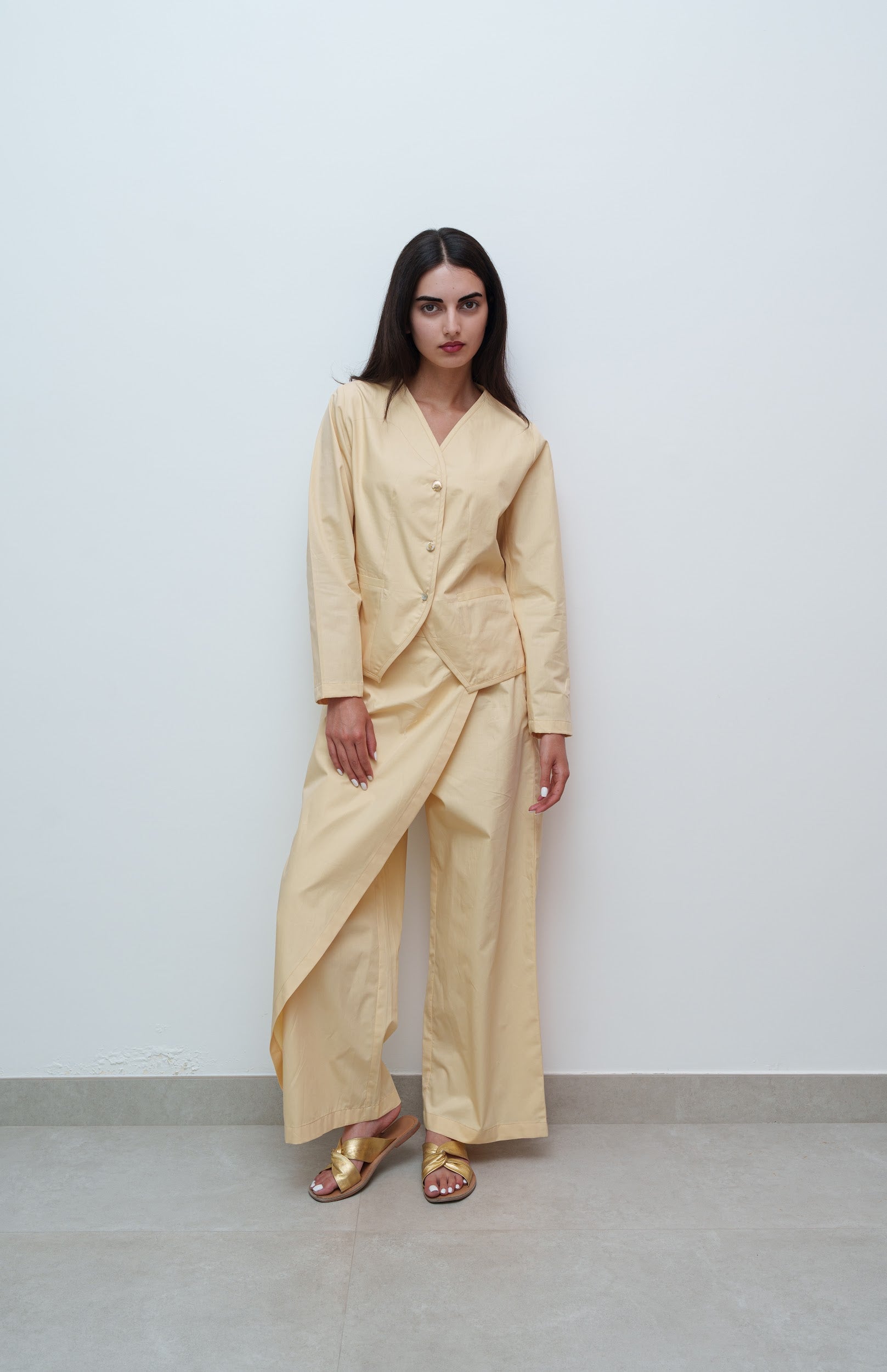 Woman wearing a beige outfit against a plain background