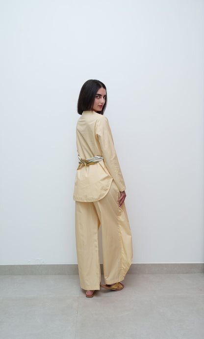Woman wearing a beige outfit with a belt against a white background