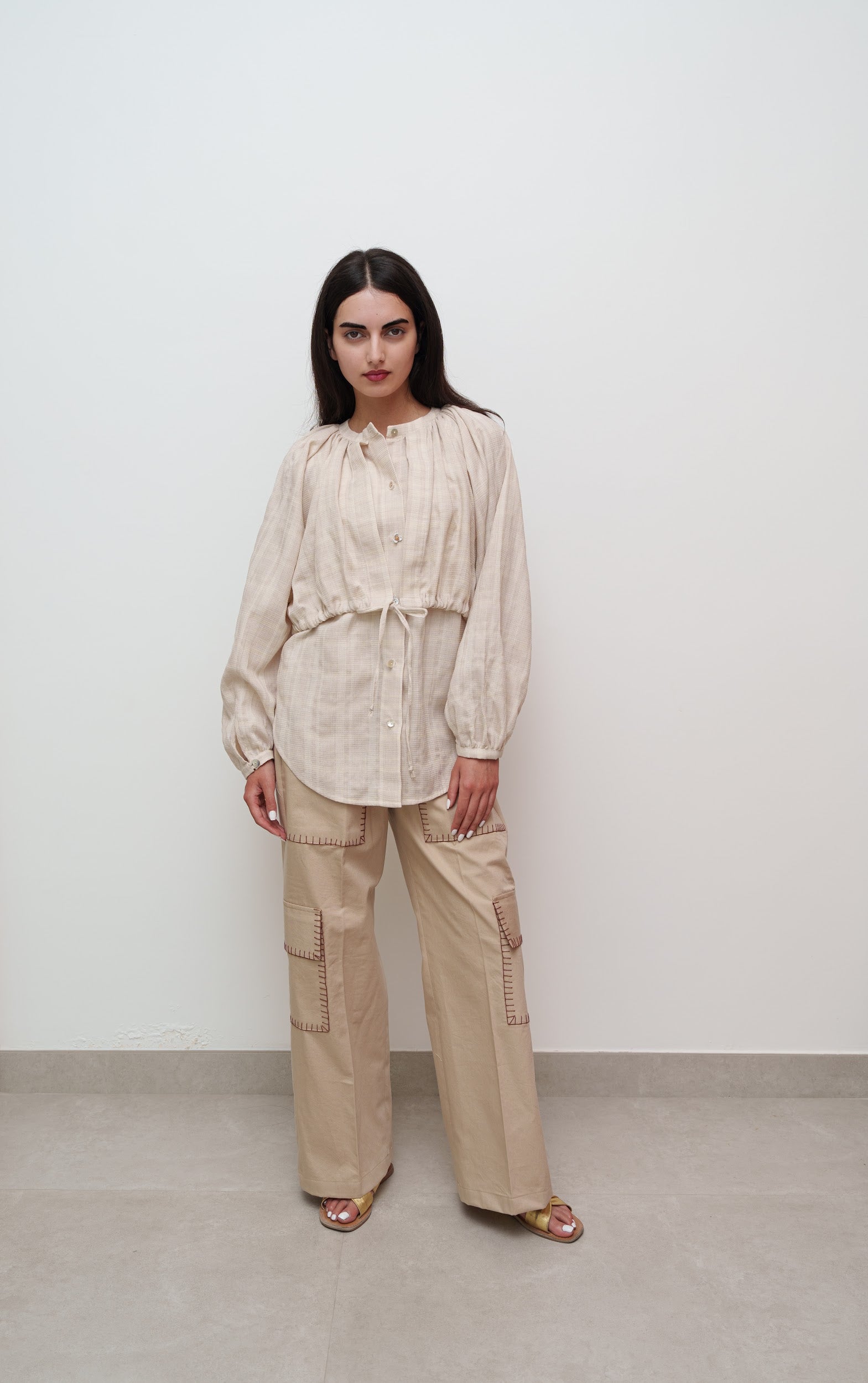 Woman wearing a beige outfit against a white background