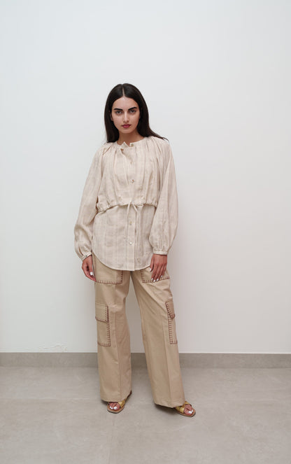 Woman wearing a beige outfit against a white background
