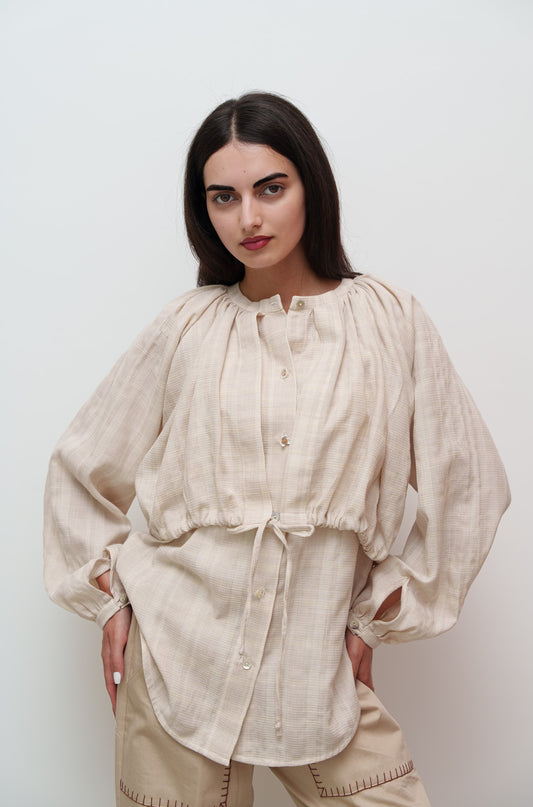 Lightweight draped shirt with feminine fit and delicate flower buttons, worn by woman on neutral backdrop