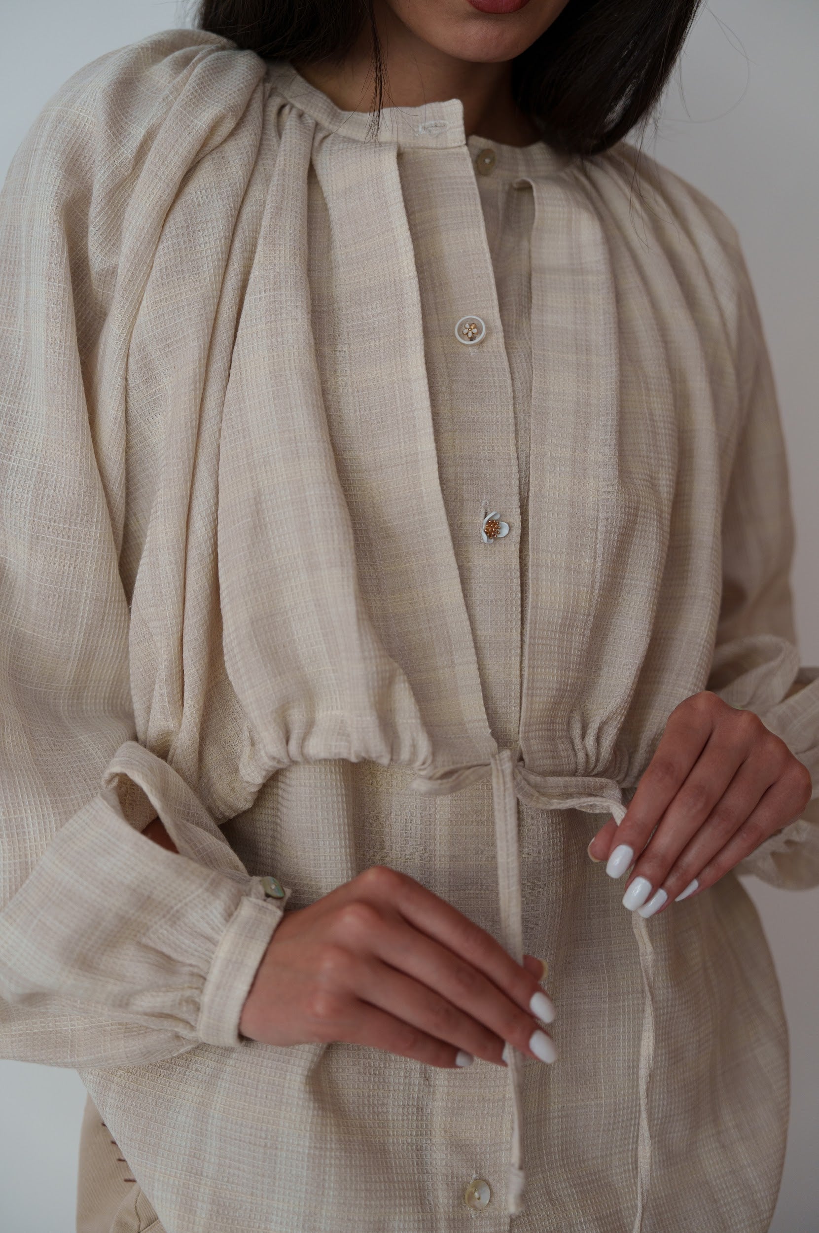 Beige dress with long sleeves and a tie waist, worn by a person.
