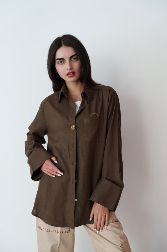 Woman in brown Egyptian linen shirt with hand embroidery and unique buttons – summer collection on white background.
