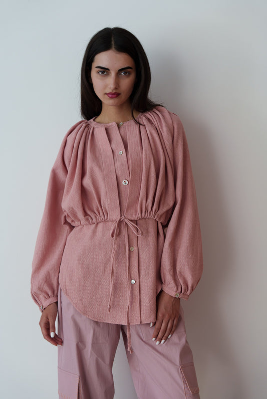 Woman wearing a pink outfit against a plain background