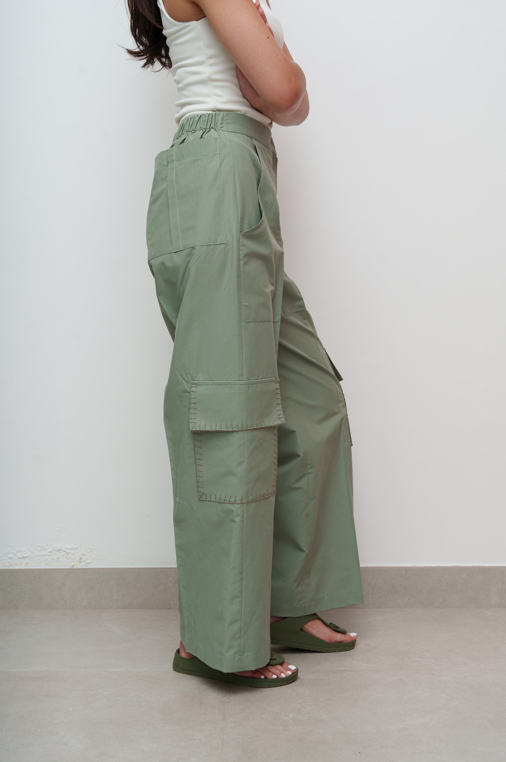 Person wearing green cargo pants against a white wall