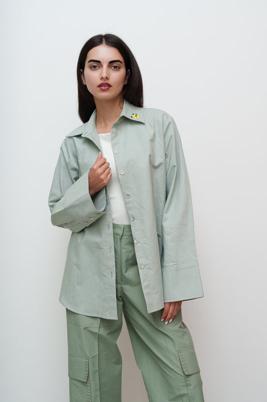 Woman wearing a light green shirt and pants against a white background