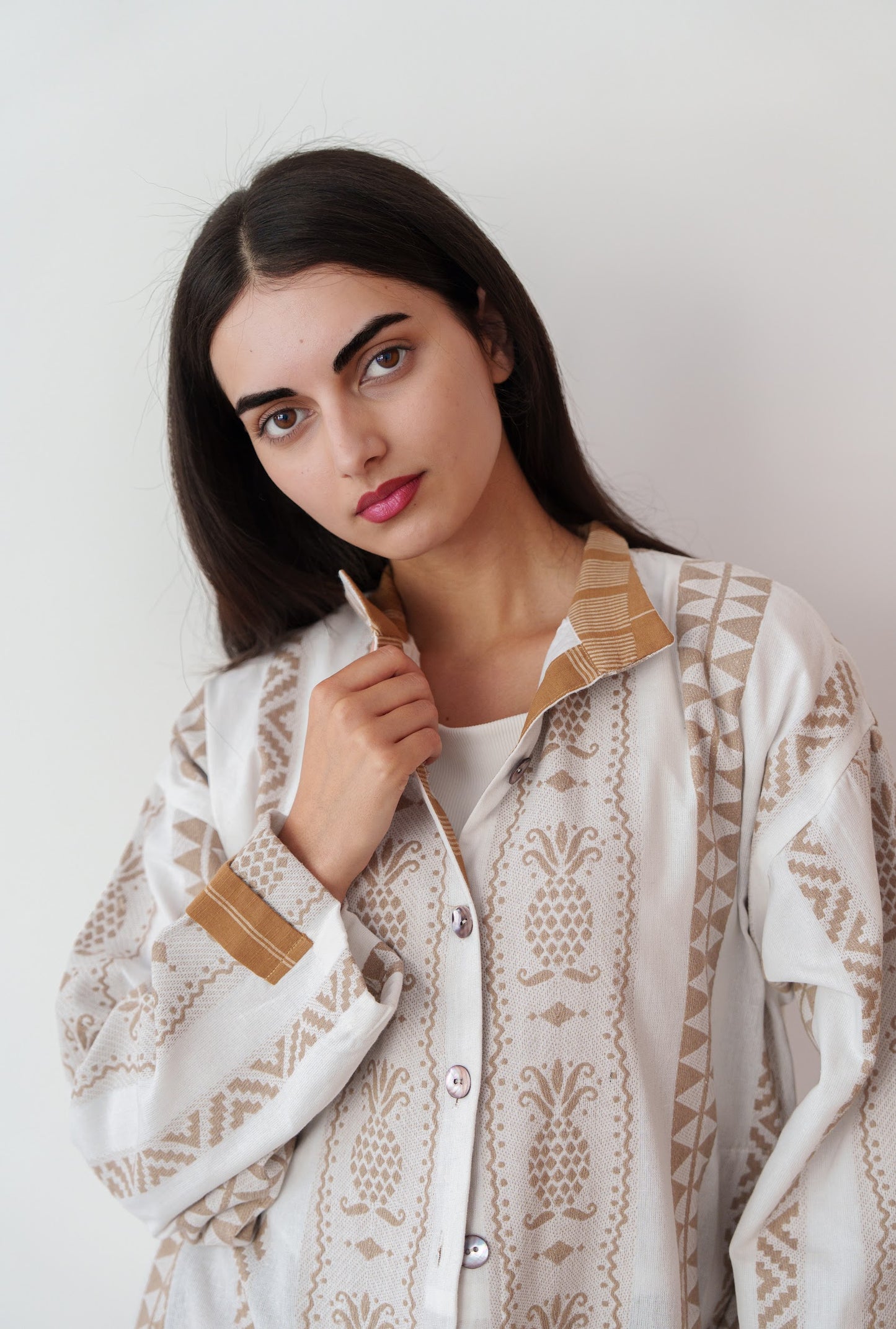 White and beige printed shirt worn by woman against a neutral plain background