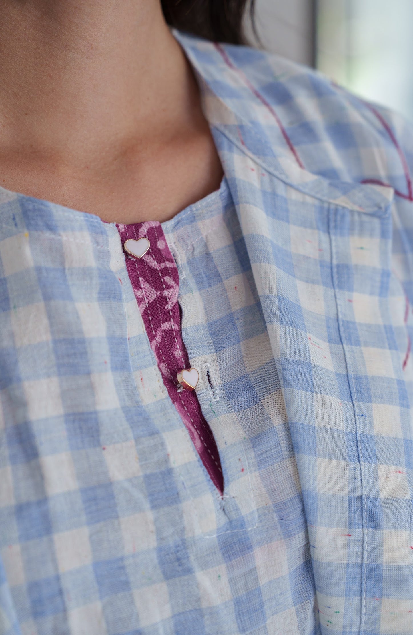 Close-up of a person wearing a blue and white checkered shirt with a pink plaid pattern.