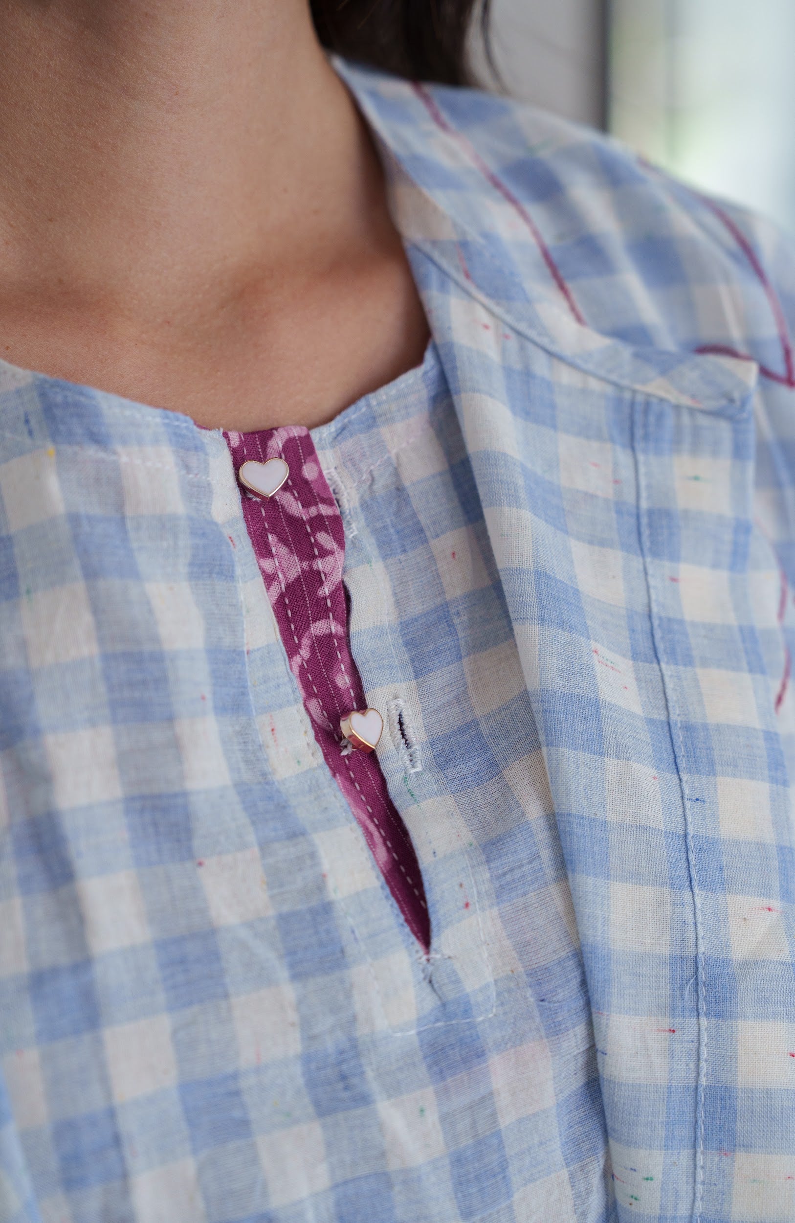 Close-up of a person wearing a blue and white checkered shirt with a pink plaid pattern.